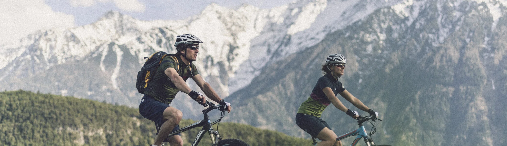 Zwei Personen fahren mit ihren Mountainbikes vor einer Bergkulisse. | © DAV/Wolfgang Ehn